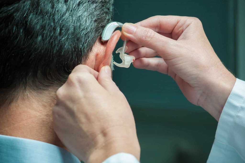 ent doctor putting on hearing aid for patient