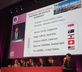 Conference panel featuring experts in rhinoplasty, with a speaker at the podium and flags representing countries