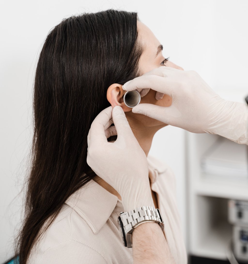 Healthcare professional with gloves adjusting an ear device on a patient