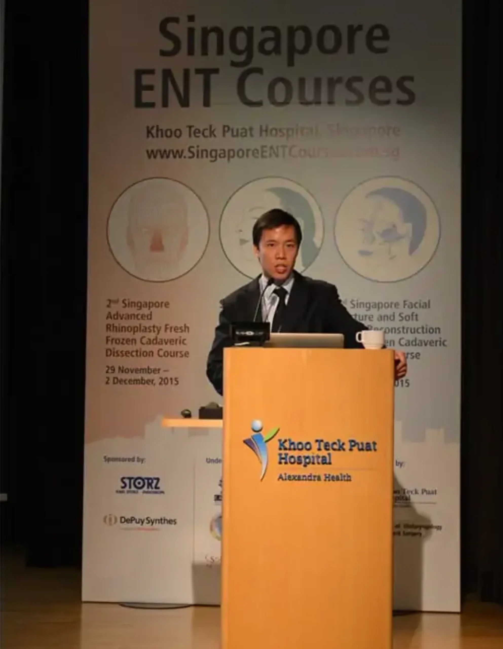Dr. Chua stands at a podium in front of a banner for Singapore ENT Courses at Khoo Teck Puat Hospital