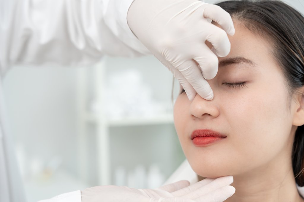 Healthcare professional in gloves examines patient face