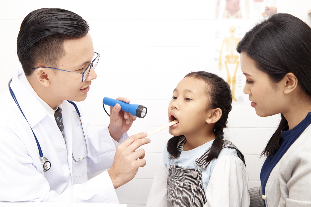 Asian man doctor talking to young child and mother