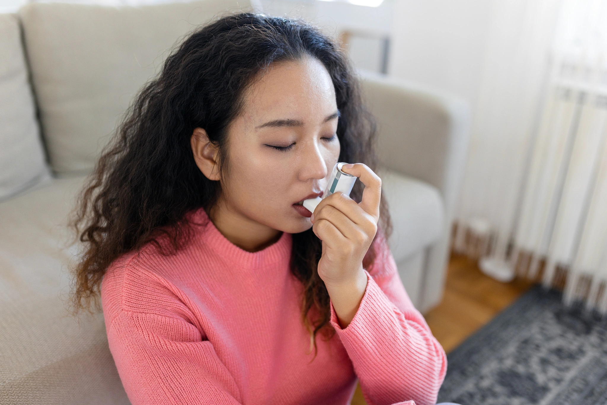 asian woman using inhaler while suffering from asthma