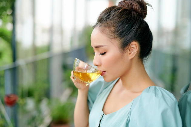 Woman drinking honey water to soothe allergic rhinitis symptoms